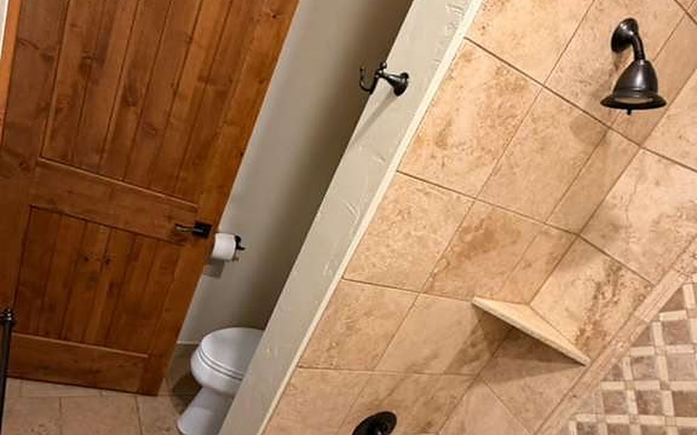 Bathroom with tiled tub surround, mosaic border and travertine floor cleaned