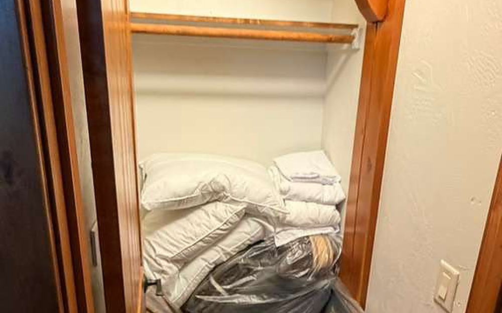 Linen closet with folded bedding and pillows stored on wood shelves