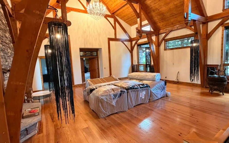 Great room under timber trusses with wrapped furniture and polished hardwood floors