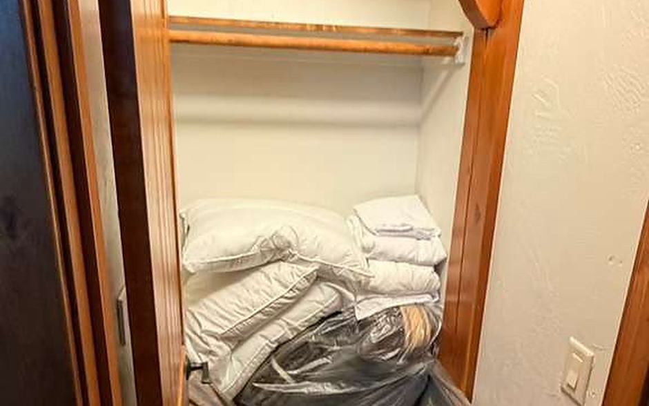 Linen closet with folded bedding and pillows stored on wood shelves