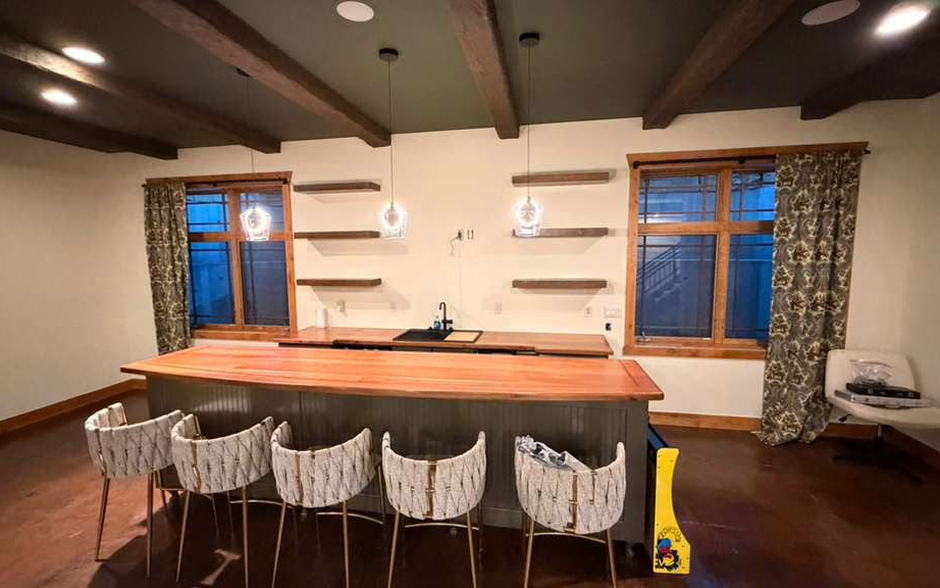 Lower-level bar with barstools, floating shelves and pendant lights cleaned