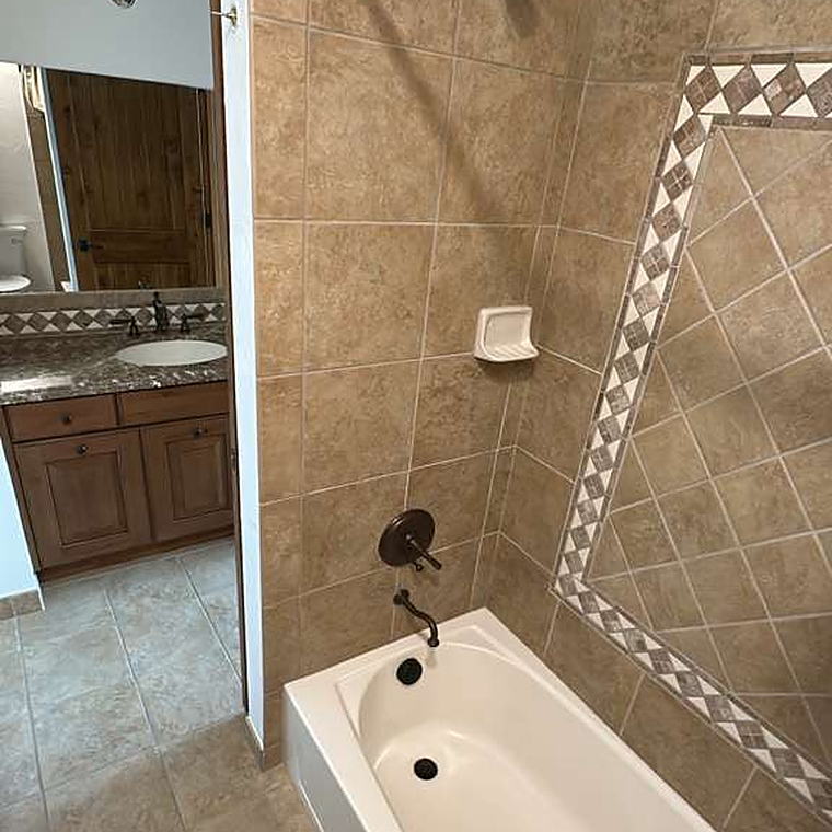 Bathtub and tiled surround with mosaic border after cleaning