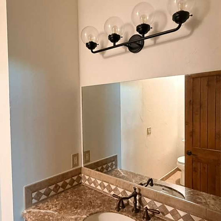Bathroom vanity with granite counter, mirror and black sconce lighting cleaned