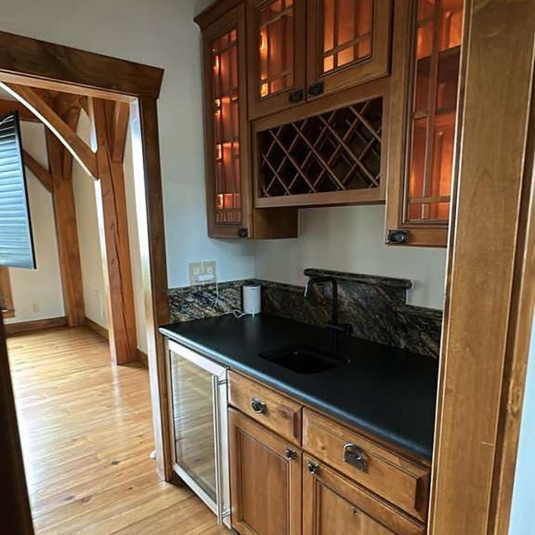 Wet bar with dark stone counter, wine rack and glass-front cabinets cleaned