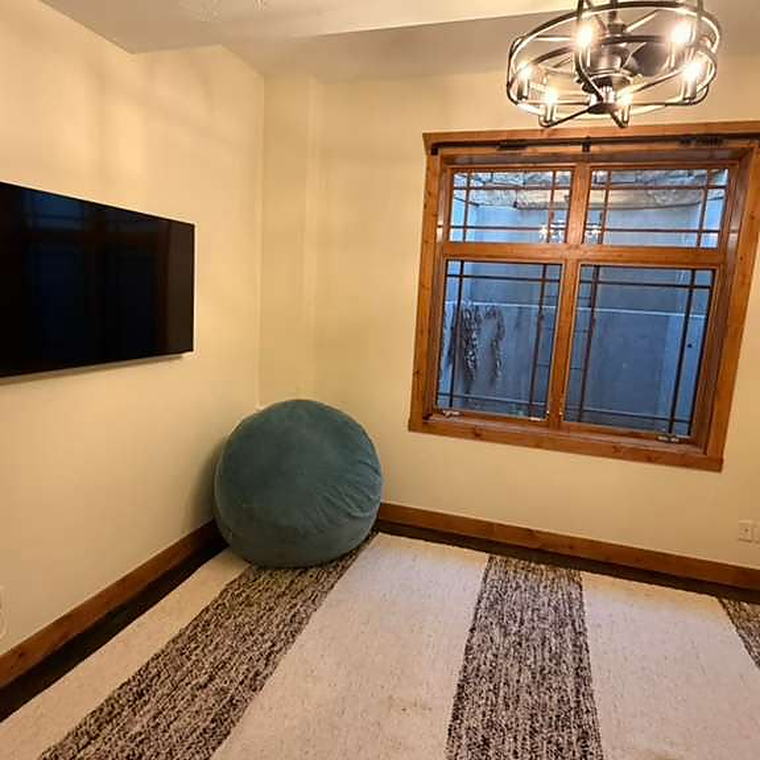 Small sitting room with a wall-mounted television and striped rug