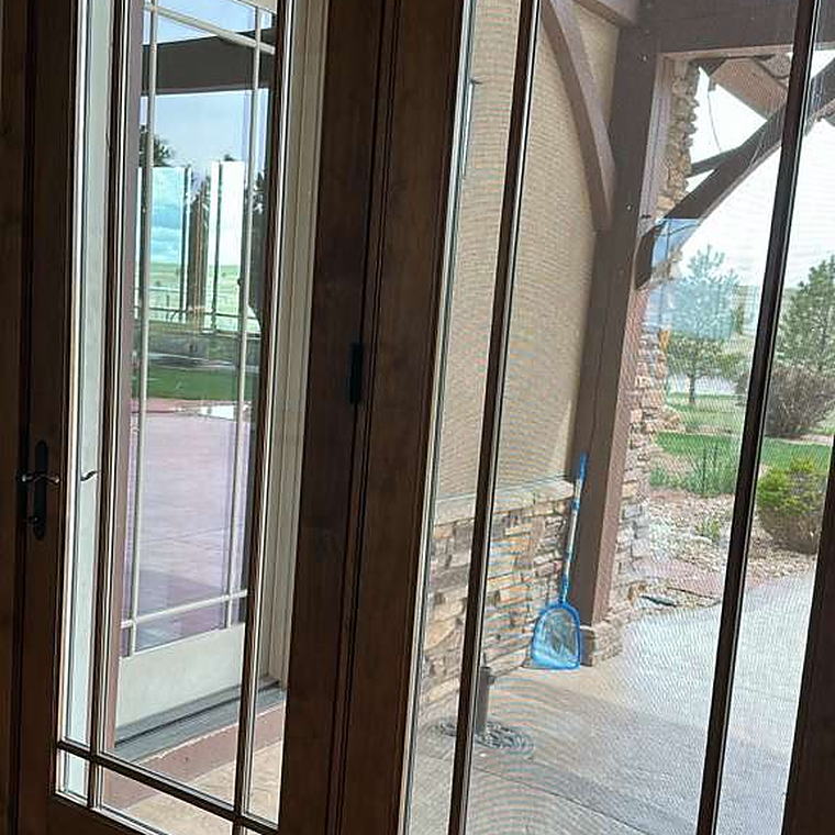 French doors with the glass cleaned, looking out to a covered porch