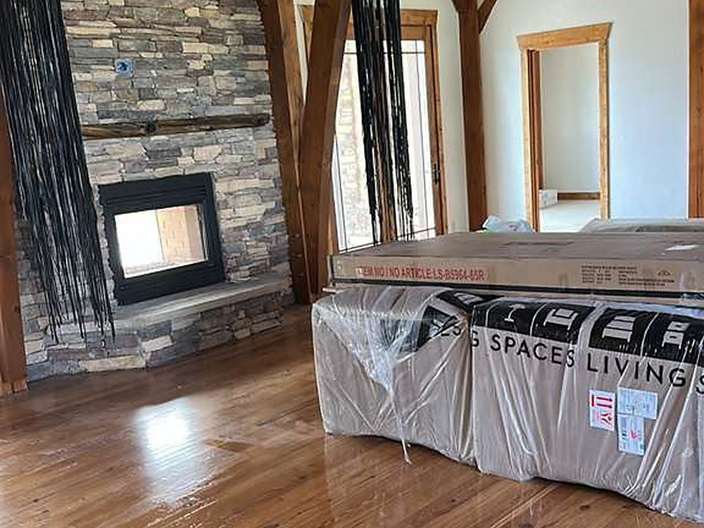 Great room with a stone fireplace and polished hardwood floor