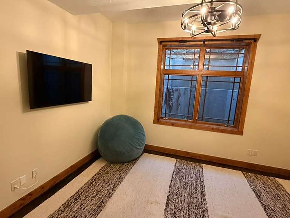 Small sitting room with a wall-mounted television and striped rug