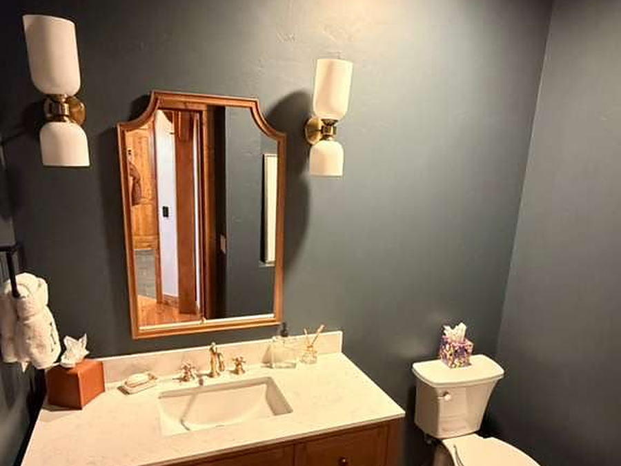 Powder room with vanity, wall sconces, mirror and folded towels set out