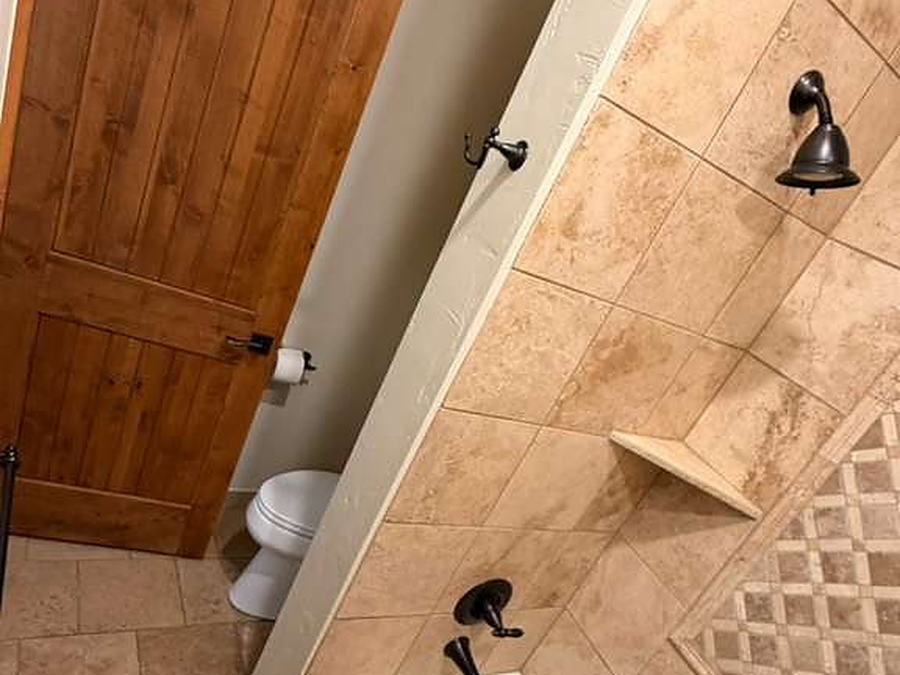 Bathroom with tiled tub surround, mosaic border and travertine floor cleaned