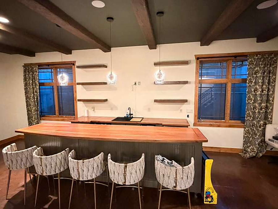 Lower-level bar with barstools, floating shelves and pendant lights cleaned