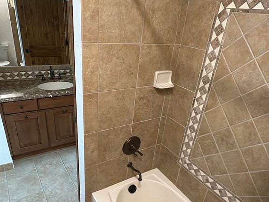 Bathtub and tiled surround with mosaic border after cleaning