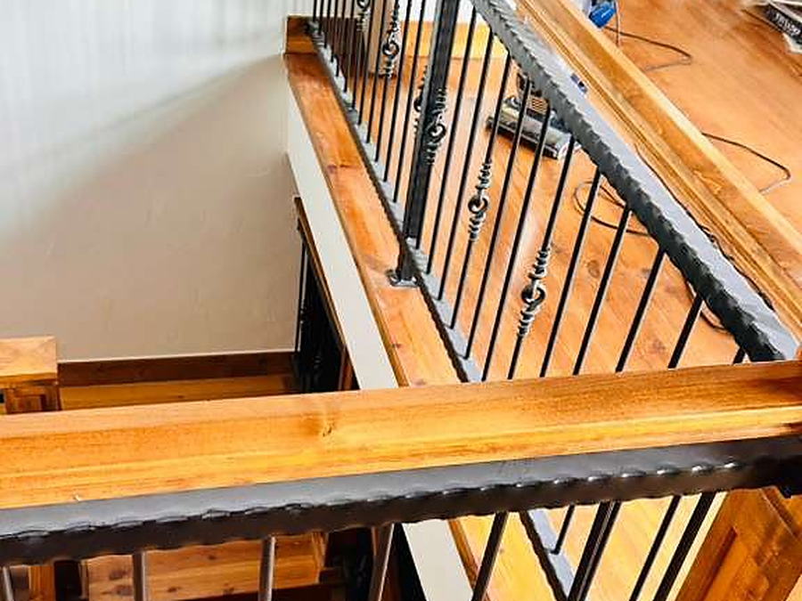 Stair railing seen from the landing, with cleaning equipment standing by