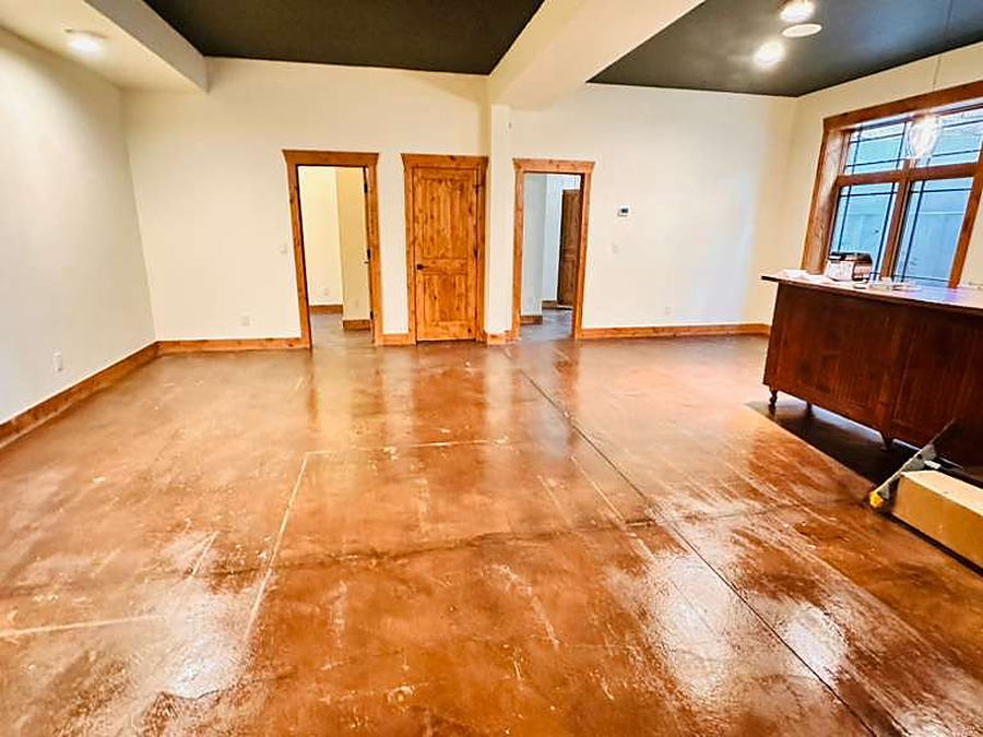 Empty room with a stained concrete floor and a wood credenza