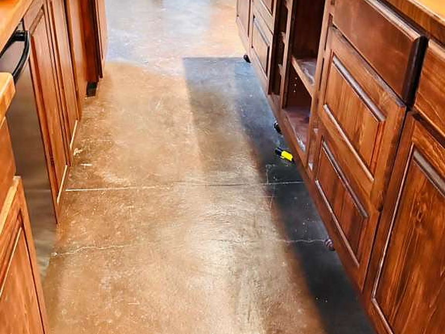 Kitchen island area with stained concrete floor cleaned and cabinet interiors wiped out