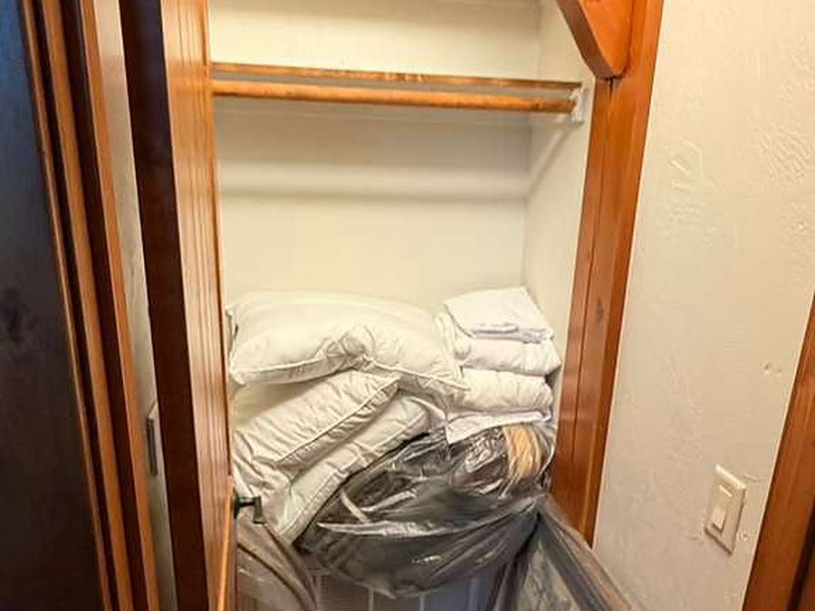 Linen closet with folded bedding and pillows stored on wood shelves