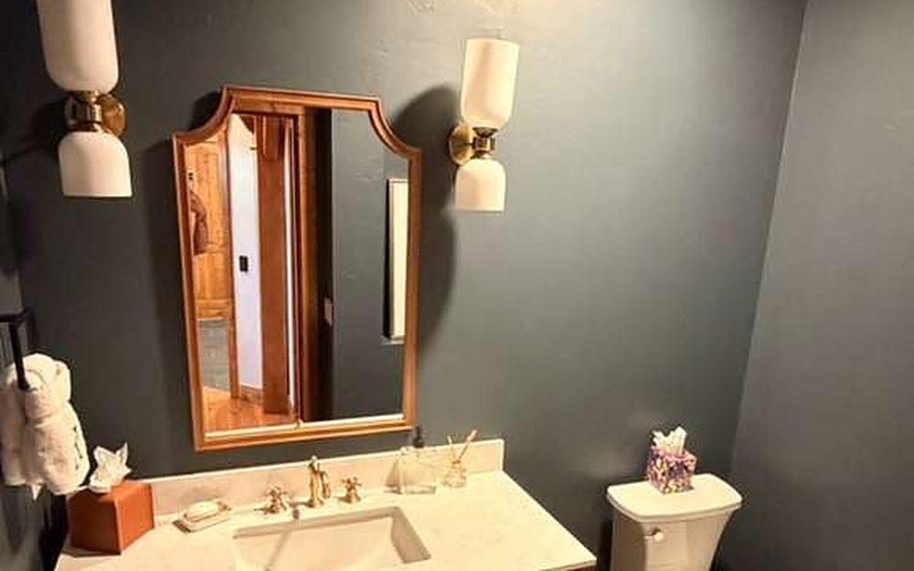 Powder room with vanity, wall sconces, mirror and folded towels set out