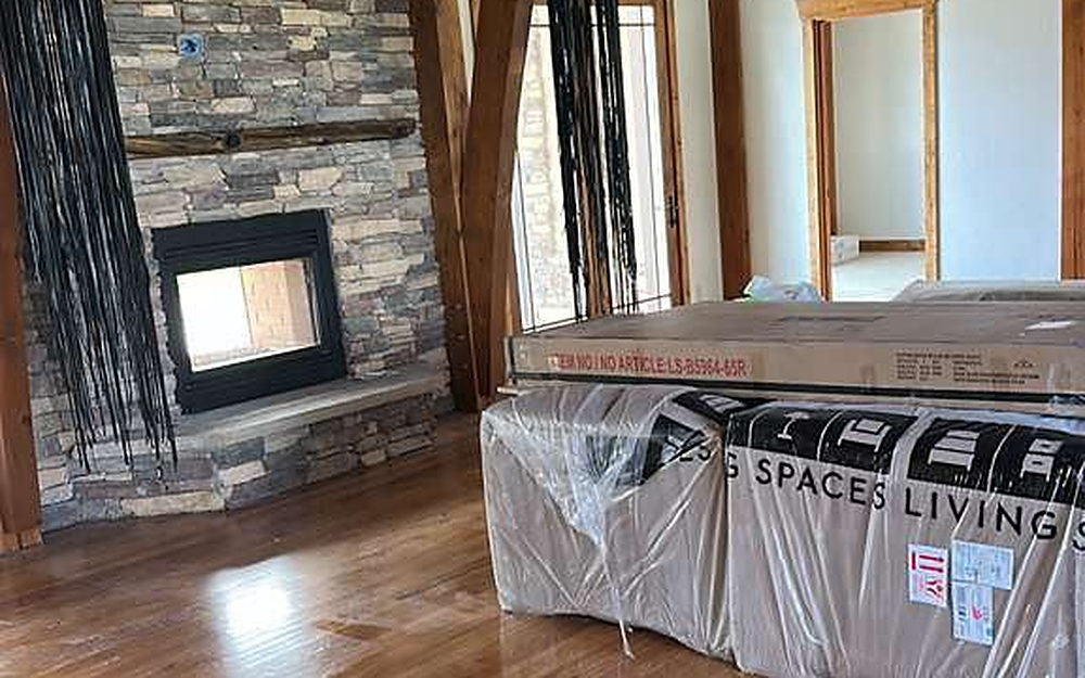 Great room with a stone fireplace and polished hardwood floor