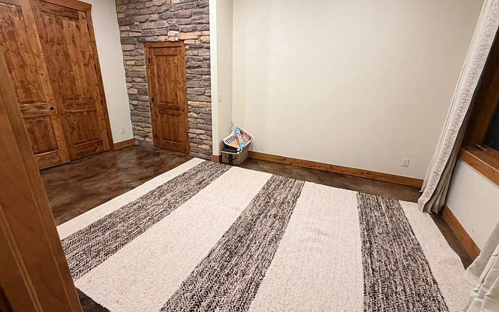 Empty room with a striped rug over a stained concrete floor